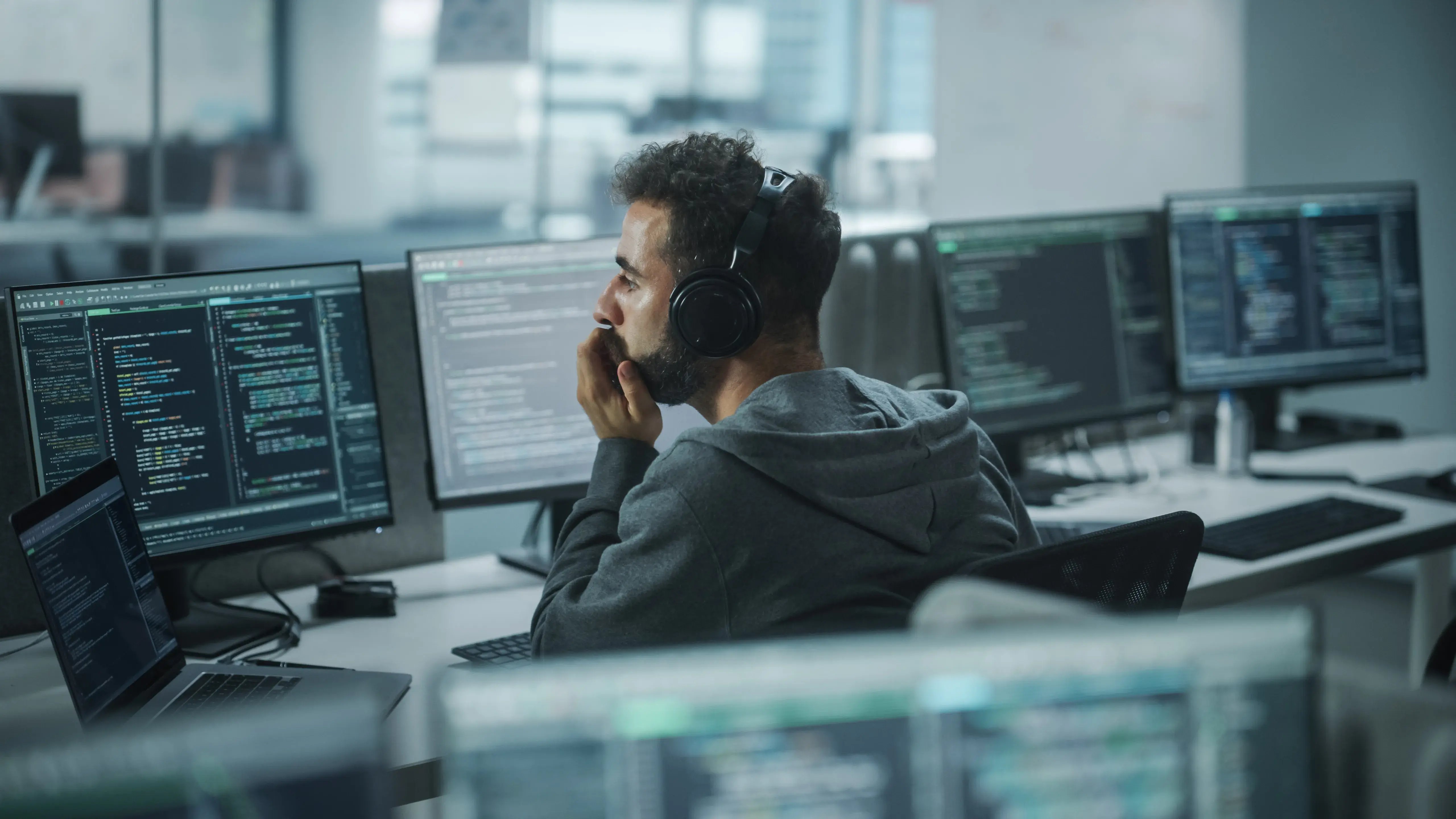 homme devant plusieurs ecrans montrant des lignes de code